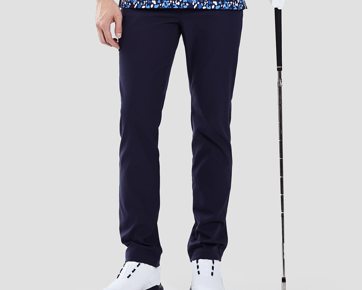 Person wearing navy golf pants with a golf club on a light gray background
