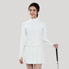 Woman wearing a white outfit with a pleated skirt, holding a golf club on a plain background