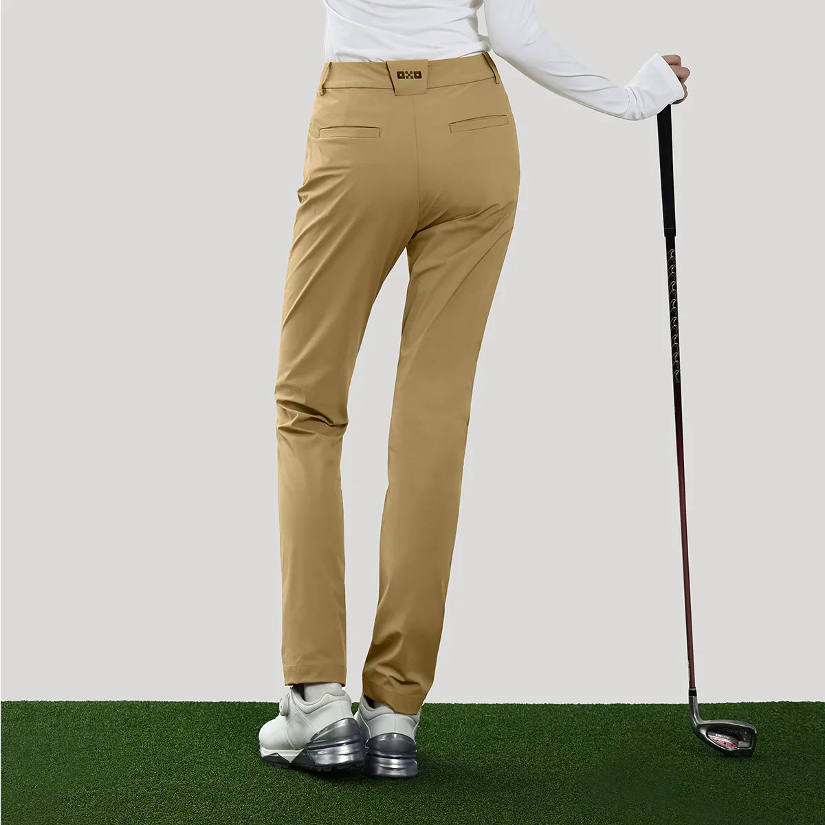 Person wearing tan golf pants on a green and white background